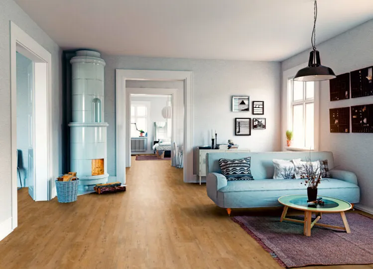 Wohnzimmer mit edlem Holzfußboden und stilvoller Einrichtung – hellblaue Couch, runder Couchtisch mit Pflanze, Kamin und natürliche Lichtverhältnisse schaffen ein wohnliches Ambiente.