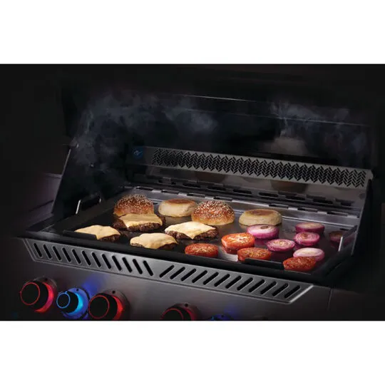 Grill mit rauchendem Rost, auf dem Burger-Brötchen, Käse-Patties, Zwiebeln und Wurstscheiben liegen – beleuchtete Bedienknöpfe vorne.